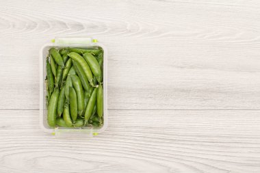 Gri arka plan üzerinde taze yeşil bezelye ile Plastik yemek hazırlık kapları.