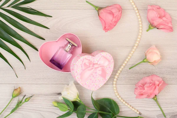 Caixa de presente com garrafa de perfume e flores em tábuas de madeira — Fotografia de Stock