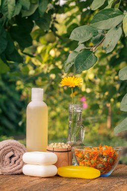 Havlu, kadife çiçeği ekstresi ile sabun, doğal arka plan ile bir şişe calendula çiçekler.