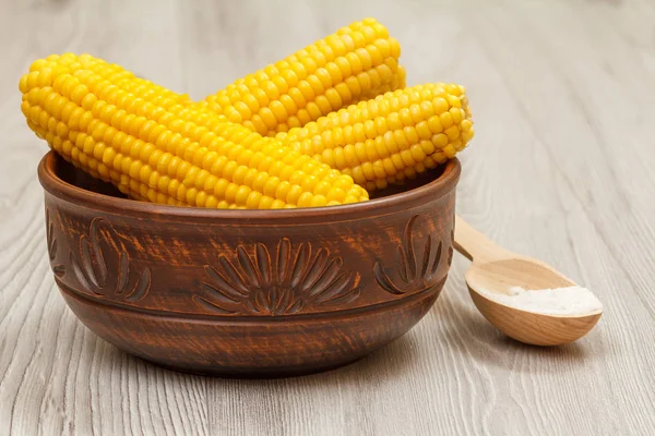 Глиняна миска з вареною кукурудзою і ложкою з сіллю на дерев'яному столі — стокове фото