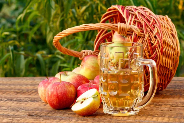 Gerade gepflückte Äpfel im Weidenkorb und Apfelmost im Glaskelch — Stockfoto