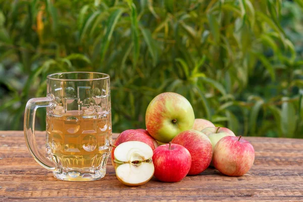 Glaskelch mit Apfelmost und geernteten Äpfeln auf Holzbrett — Stockfoto