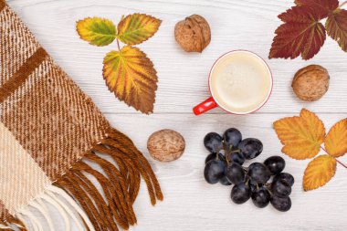 Sonbahar teması. Ekose, kuru yapraklar, bir fincan kahve, üzüm ve ceviz ahşap arka plan üzerinde.