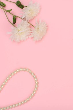 Pembe arka planda beyaz boncuklar ve çiçekler.