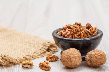 Ahşap bir arka plan üzerinde çuval bezi ile taş kase ceviz.