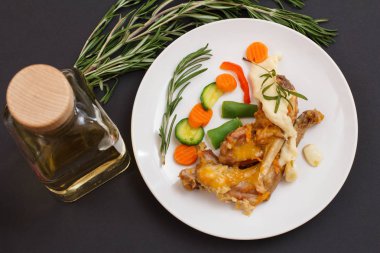 Tavşan bacakları seramik tabakta beşamel sos ile beyaz şarap pişmiş.