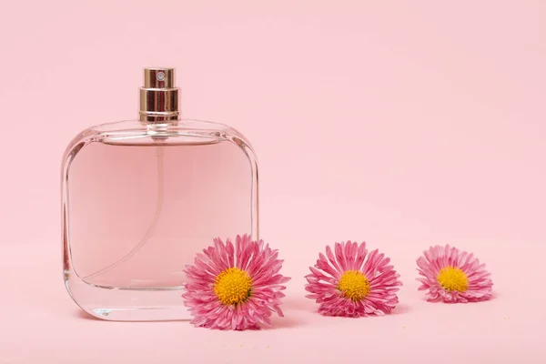 Perfumy damskie z kwiatami na różowym tle. — Zdjęcie stockowe