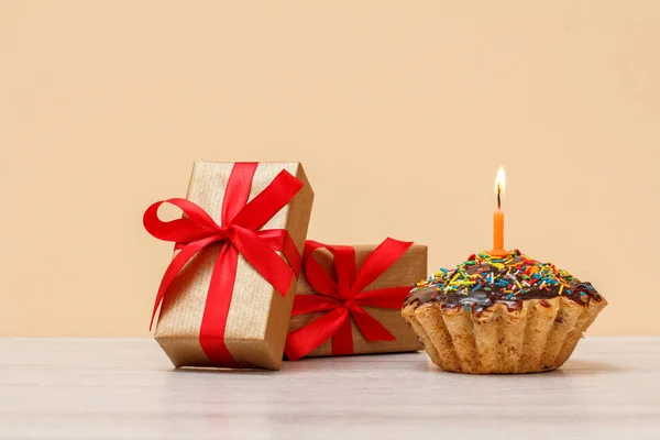 Ízletes születésnapi Muffin égő ünnepi gyertya és Ajándékdobozok. — Stock Fotó