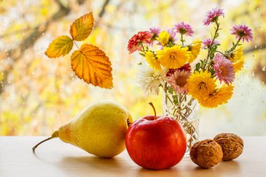 Elma, armut, ceviz, çiçekler ve sonbahar sarı yaprak pencere cam üzerinde bulanık arka planda su damlaları.