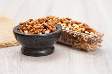 Ahşap bir arka plan üzerinde taş kase ve plastik kap ceviz.