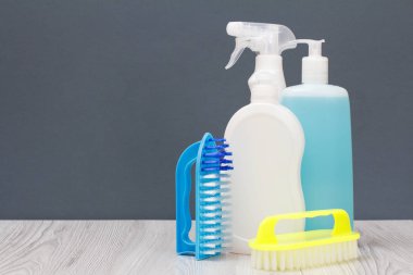Gri arka planda bulaşık sıvısı ve fırça şişeleri.