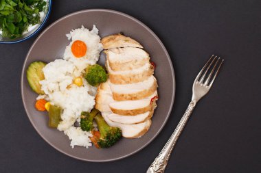 Fırında tavuk göğüsleri veya tepside pirinç ve sebze ile plaka üzerinde fileto.