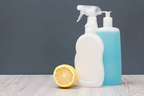 Botellas de líquido lavavajillas y limón sobre fondo gris . — Foto de Stock