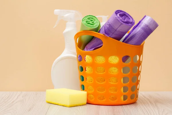 Botellas de líquido lavavajillas, cesta con bolsas de basura y esponjas en escritorio de madera . —  Fotos de Stock