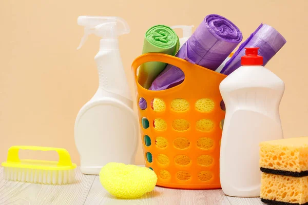 Garrafas de líquido de lavagem de louça, cesta com sacos de lixo e esponjas em mesa de madeira . — Fotografia de Stock