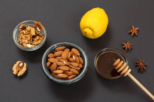 Health remedy relief foods for cold and flu with lemon, honey and walnuts on a black background. Top view. Foods That Boost the Immune System.