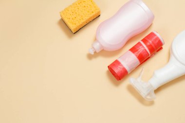 Plastik cam ve fayans temizleyicisi mikrodalga fırınlar ve fırınlar için deterjan, bej arka planda çöp torbaları ve sünger. Üst Manzara. Yıkama ve temizleme seti.