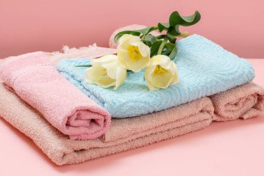 Pembe arka planda sarı laleli yumuşak havlu yığını..