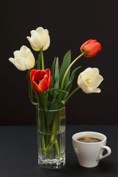 Bukiet Żółtych Tulipanów Szklanym Wazonie Filiżanka Kawy Czarnym Tle — Zdjęcie stockowe
