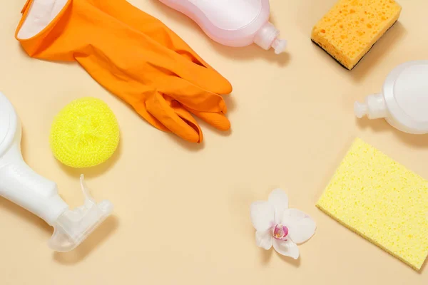 Plastic bottles of dishwashing liquid, glass and tile cleaner, detergent for microwave ovens and stoves, rubber gloves and sponges on a beige background. Top view. Cleaning set.