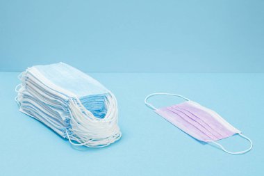 Mavi arka planda tıbbi koruyucu maske yığını. Viral enfeksiyonlara karşı kişisel koruma ekipmanları.