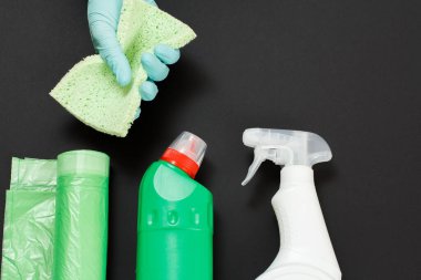 Siyah arka planda temizleme ve yıkama seti olan nitril eldivenli bir kadın eli. Üst görünüm.