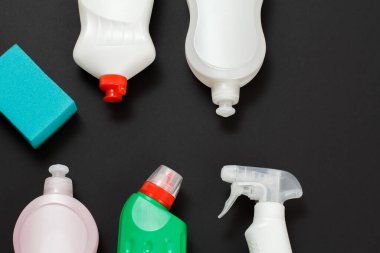 Plastik deterjan şişeleri ve siyah arka planda bir sünger. Üst Manzara. Yıkama ve temizleme seti.