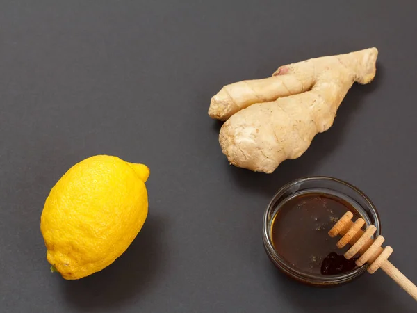 Health remedy relief foods for cold and flu with lemon, ginger and honey on a black background. Top view. Foods That Boost the Immune System.