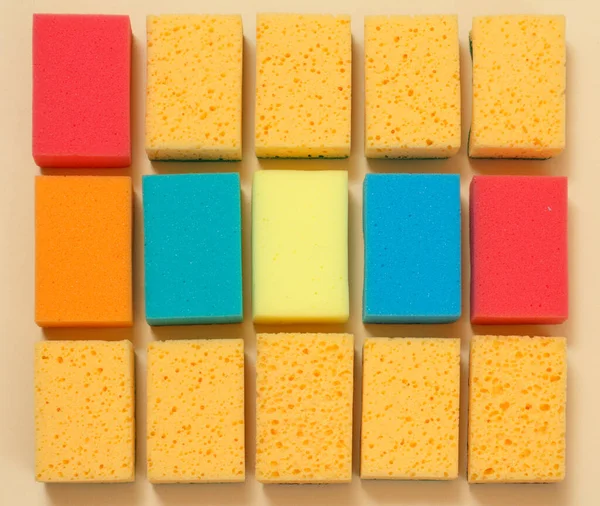Sponges of different colors on a beige background. Top view. Washing and cleaning set.