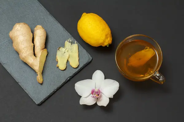 Health remedy foods for cold and flu relief with lemon, ginger and tea on a black background. Top view. Foods That Boost the Immune System.