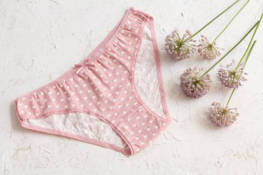 Beyaz yapılı arka planda yaz çiçeği olan pembe pamuklu külot. Kadın iç çamaşırı seti. Üst görünüm.