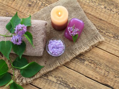 Tuvalet prosedürleri için Terry havlusu, sabun ve deniz tuzu yanan mum ve çuval bezinde leylak çiçekleri ve eski ahşap tahtalar. Üst Manzara. Spa ürünleri ve aksesuarları.