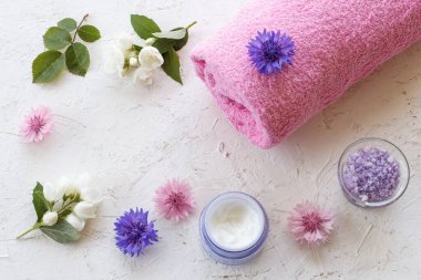 Beyaz arka planda deniz tuzu, cilt kremi, havlu, yasemin ve mısır çiçeği konserveleri. Kadın kozmetik ürünleri ve aksesuarlar. Üst görünüm.