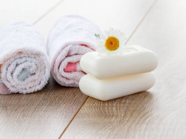 Banyo prosedürleri için beyaz havlu ve sabun ve tahta tahtalarda papatya çiçeği. Spa ürünleri ve aksesuarları