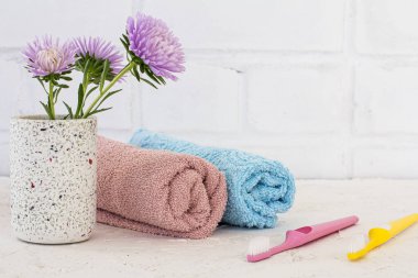 Kasımpatı çiçekleri, havlular ve beyaz arka planda diş fırçaları. Kadın kozmetik ürünleri ve aksesuarları.