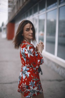 kadın Pencerenin kenarında yürüyor. kısa saçlı, kırmızı tulum tropikal süsleme ile yürüyüş esmer kız.