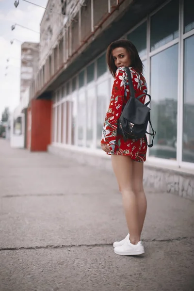 De vrouw loopt bij het raam. meisje met kort haar, brunette wandelen in rode overall met tropische sieraad. — Stockfoto