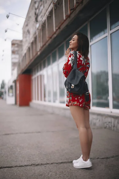 De vrouw loopt bij het raam. meisje met kort haar, brunette wandelen in rode overall met tropische sieraad. — Stockfoto