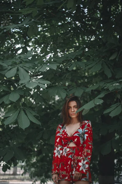 Sexy Frau unter der Kastanie. Mädchen in rotem Overall in tropischem Ornament gekleidet.model ip posiert. — Stockfoto