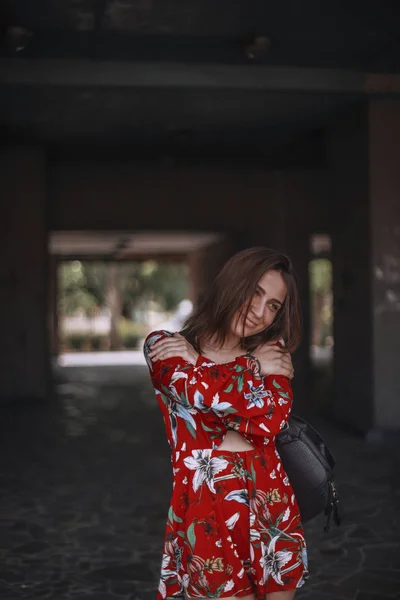 Frau in rotem Overall mit tropischen Ornamenten hängt sich auf. Brünette mit Haarschnitt Blick nach unten. — Stockfoto