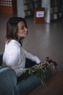 Güzel bir kız bir mavi kadife sandalyede oturan ve istirahat ediyor. Siyah pantolon ve beyaz gömlek bir kadın. kısa saçlı esmer. iş kadını ofiste.