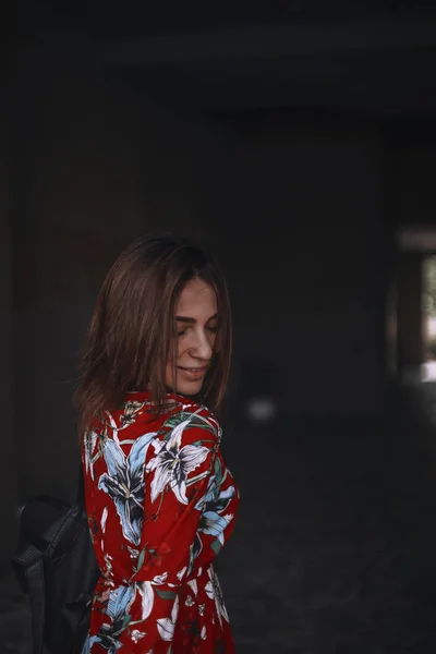 Mulher de macacão vermelho eith ornamentos tropicais está se enforcando. morena com corte de cabelo olhar para baixo . — Fotografia de Stock