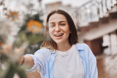 güzel bir kadın bir buket çiçek verilir. mavi bir gömlek ve T-shirt ile alan buket alır bir beyaz giymiş bir esmer. Bayan mutlu ve ile yüz.