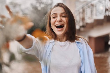 güzel bir kadın bir buket çiçek verilir. mavi bir gömlek ve T-shirt ile alan buket alır bir beyaz giymiş bir esmer. Bayan mutlu ve ile yüz.