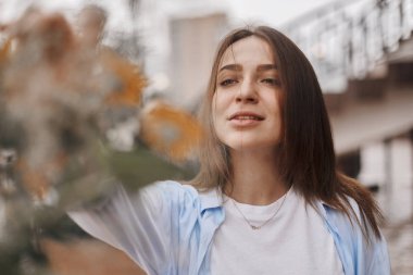 güzel bir kadın bir buket çiçek verilir. mavi bir gömlek ve T-shirt ile alan buket alır bir beyaz giymiş bir esmer. Bayan mutlu ve ile yüz.