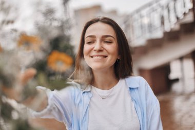 güzel bir kadın bir buket çiçek verilir. mavi bir gömlek ve T-shirt ile alan buket alır bir beyaz giymiş bir esmer. Bayan mutlu ve ile yüz.