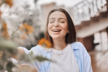 güzel bir kadın bir buket çiçek verilir. mavi bir gömlek ve T-shirt ile alan buket alır bir beyaz giymiş bir esmer. Bayan mutlu ve ile yüz.