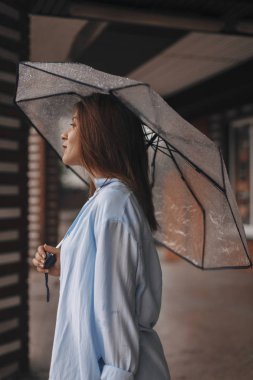 Şemsiye giyen altında çekici kadın mavi gömlek. Kız bak mutlu. Yağmur