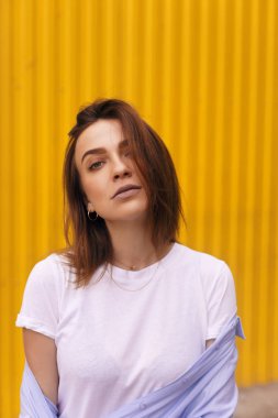 Çekici kadın portre sarı zemin üzerine. o kendini beğenmiş kameraya bakmak veya çözmemize. Kısa saçlı esmer kız.