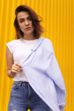 Çekici kadın portre sarı zemin üzerine. o kendini beğenmiş kameraya bakmak veya çözmemize. Kısa saçlı esmer kız.